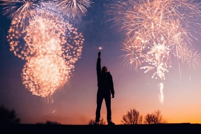 Person celebrating under vibrant fireworks