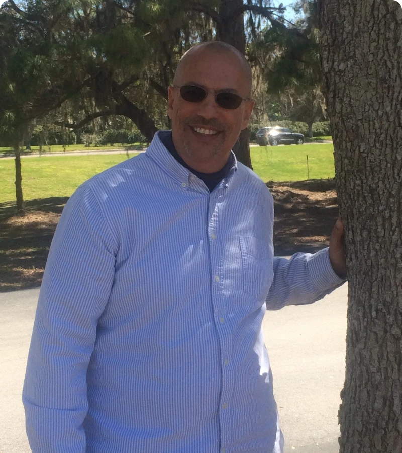 Man in striped shirt by a tree