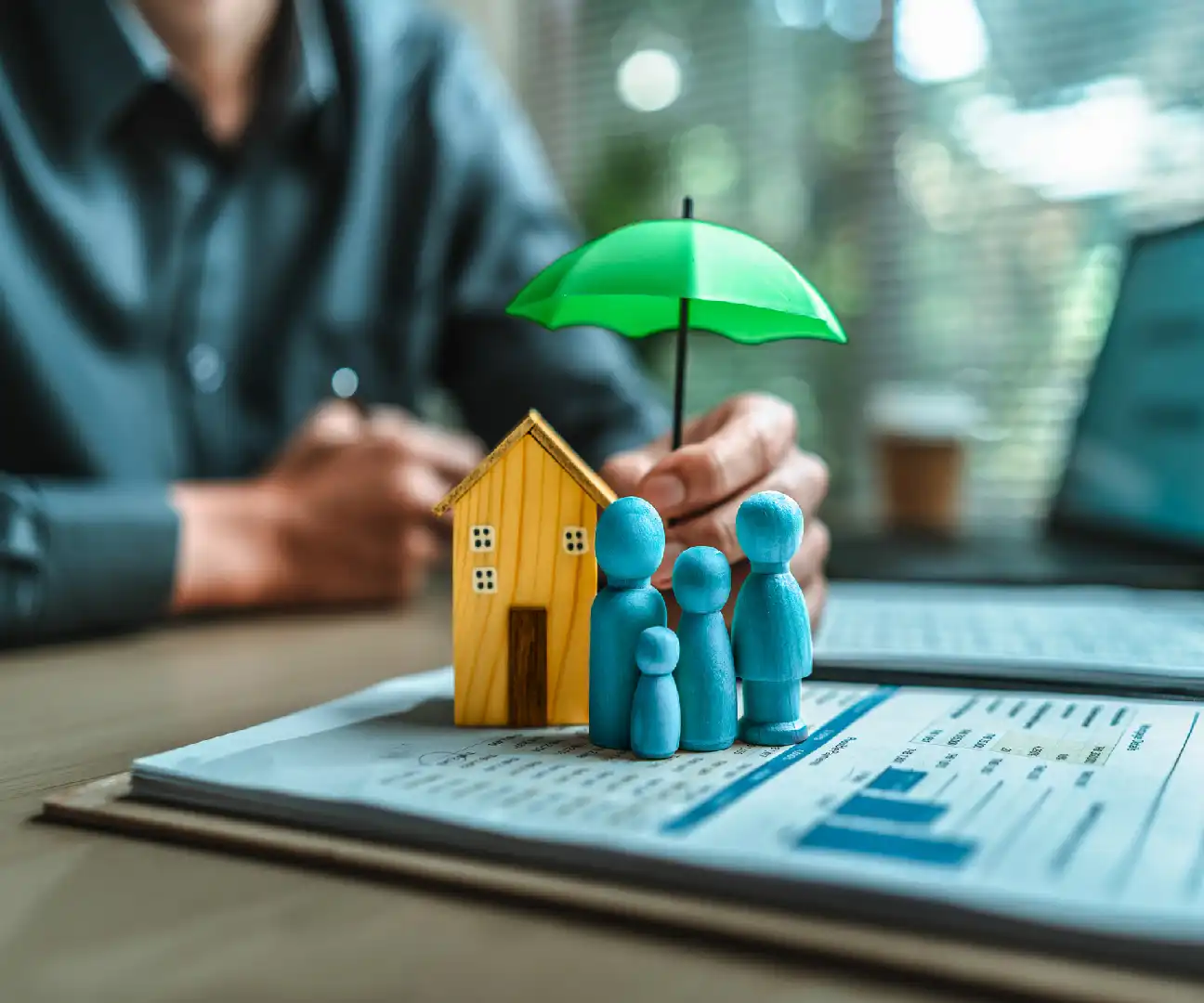 A small house and family figures protected by a green umbrella on financial documents.
